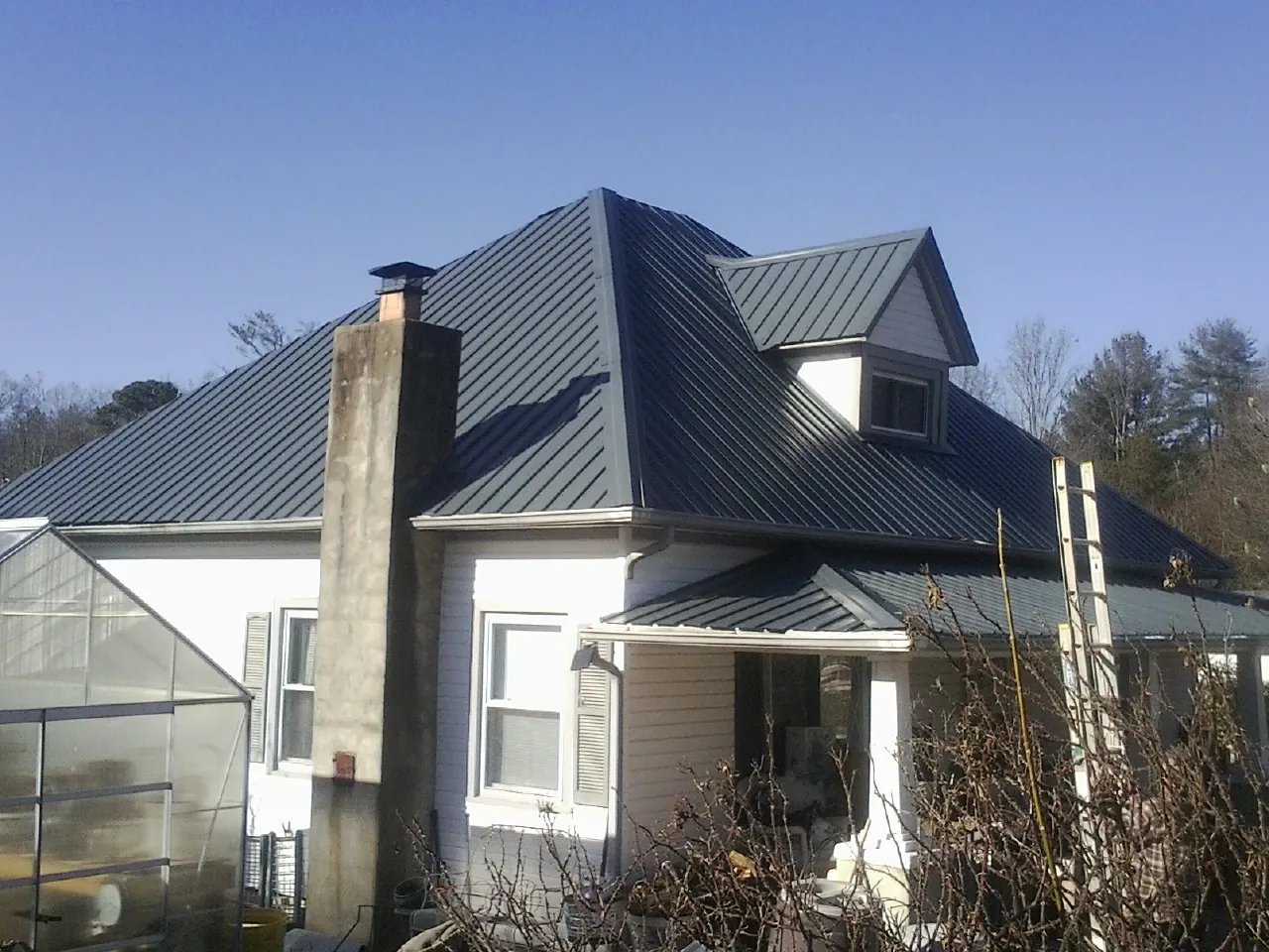 Dark blue standing seam metal roof on a white farmhouse with dormer — Slate & Tile Roof Repair by Roofing Brothers in Longview